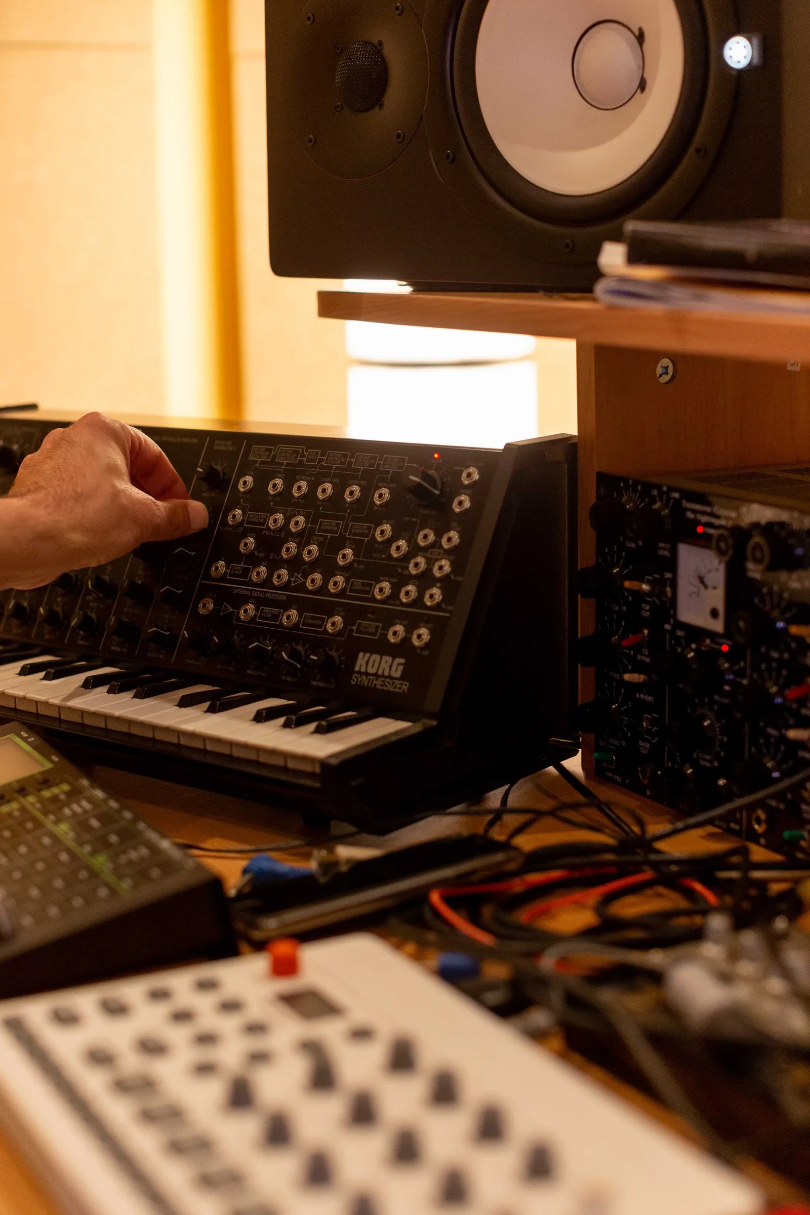 Una mano sui controlli di un synth analogico, nella luce calda dello studio